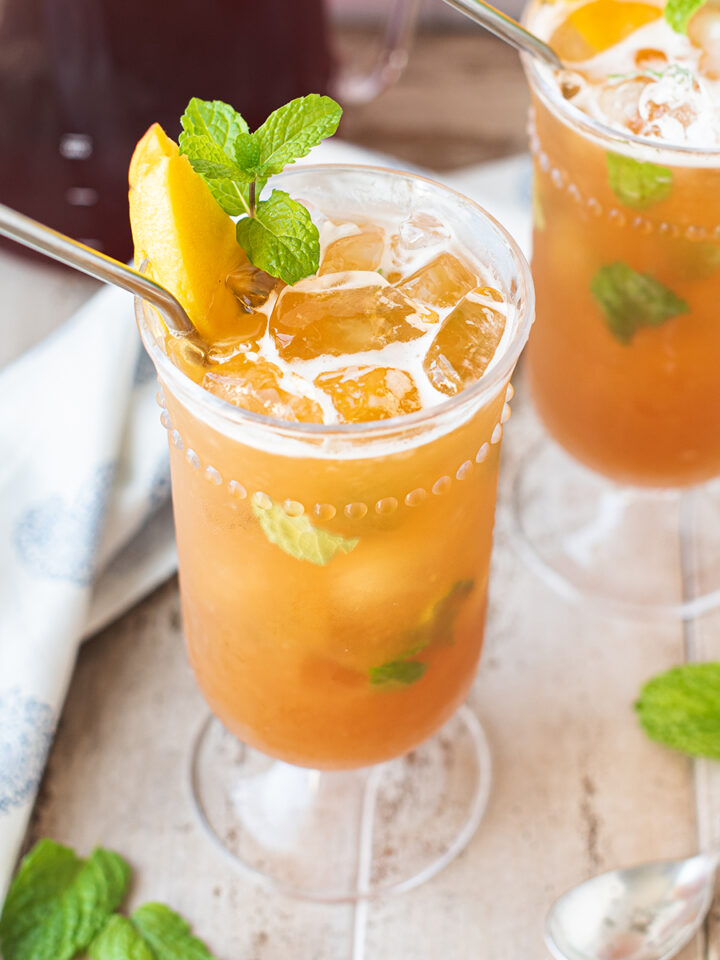 twisted iced tea cocktail garnished with mint and mango slice