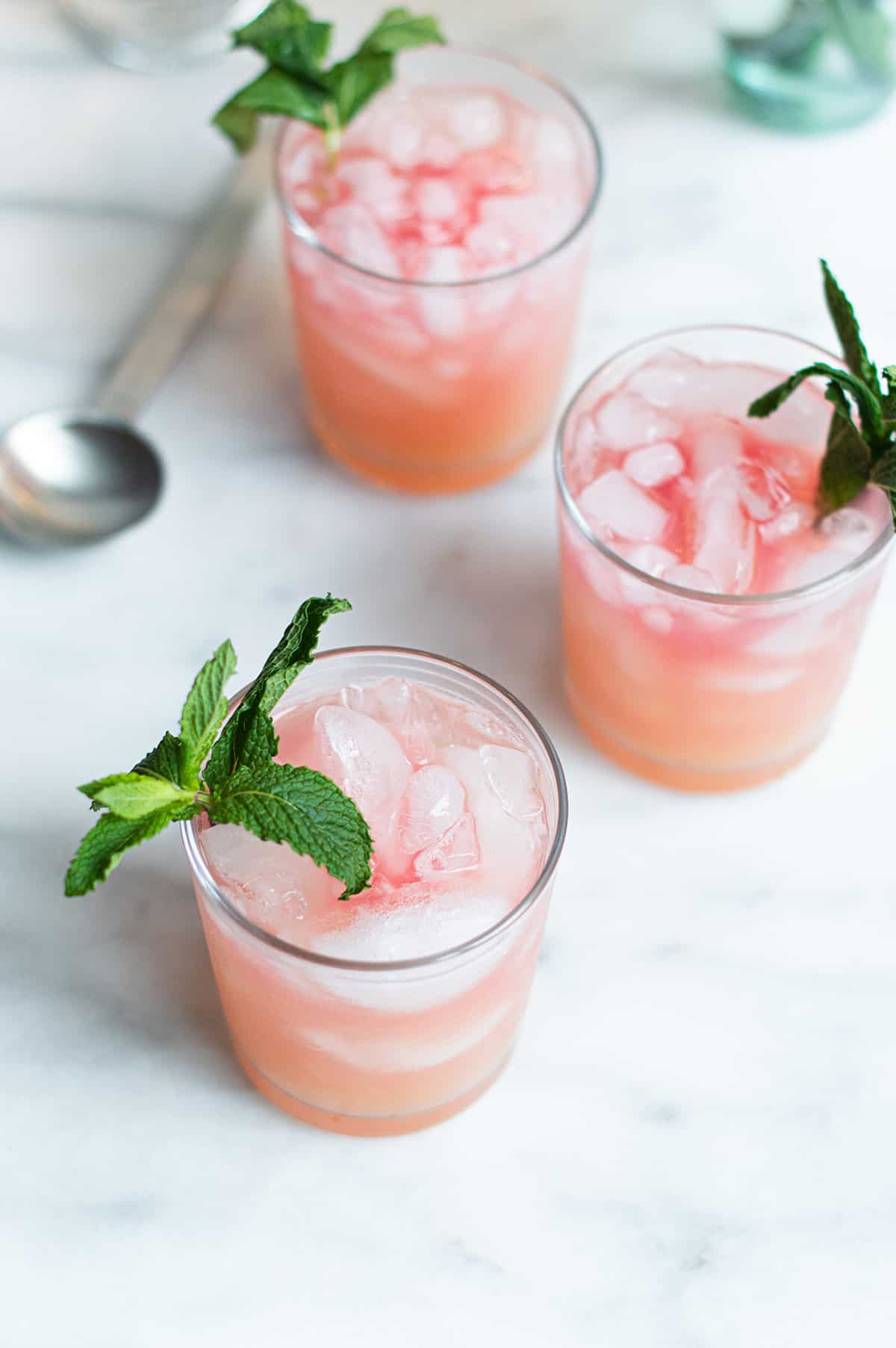 three Pink Señorita cocktails, garnished with mint on marble surface