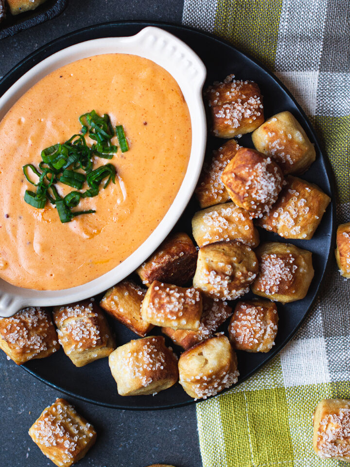 pretzel bites with plate of beer cheese on checked napkin
