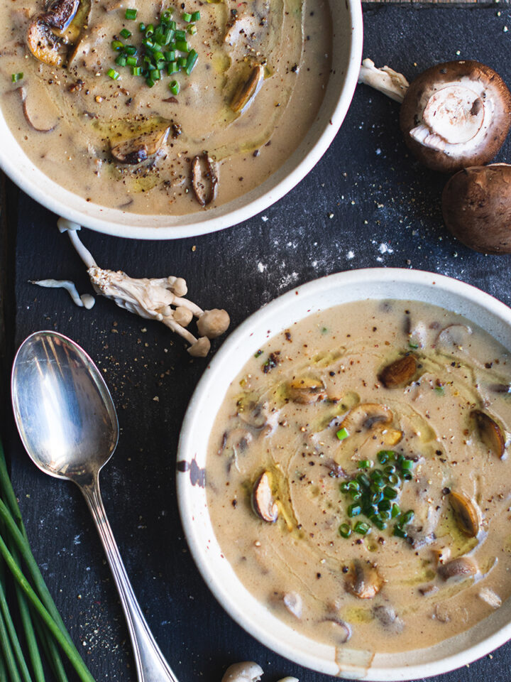 2 bowls of mushroom soup on black platter with spoon