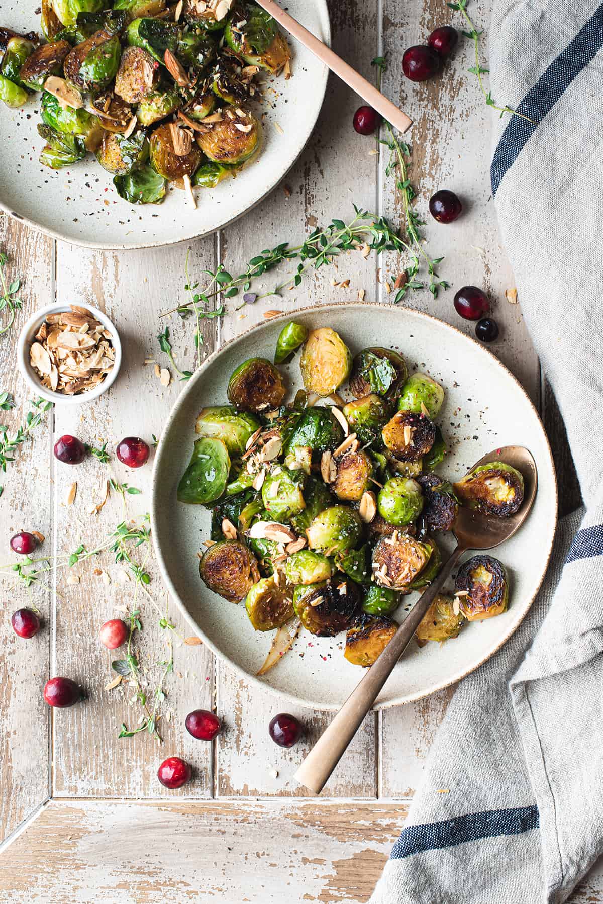 bowl of Roasted Brussels sprouts on wooden table with linen napkin + spoon