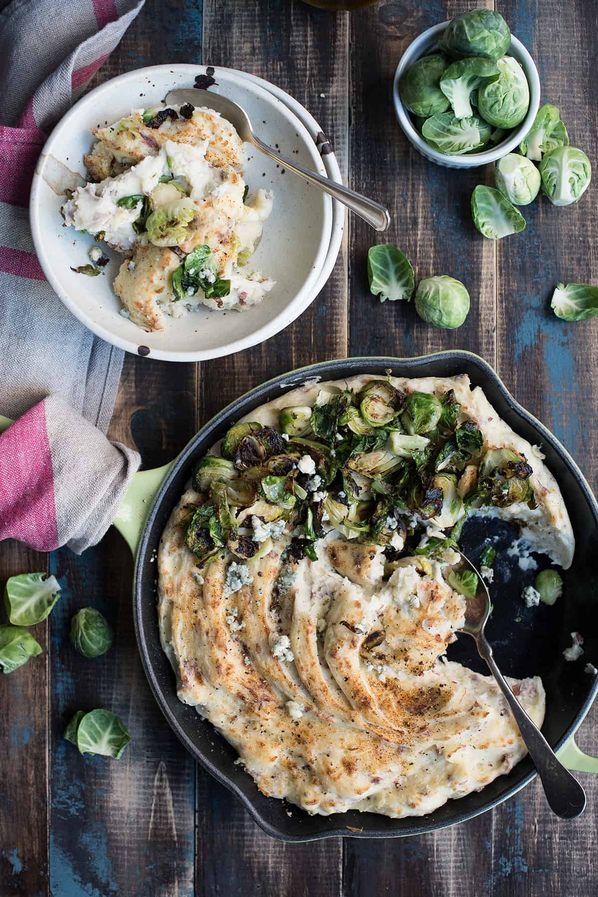 Broiled Mashed Potatoes with Roasted Sprouts in cast iron skillet, some eaten, with spoon