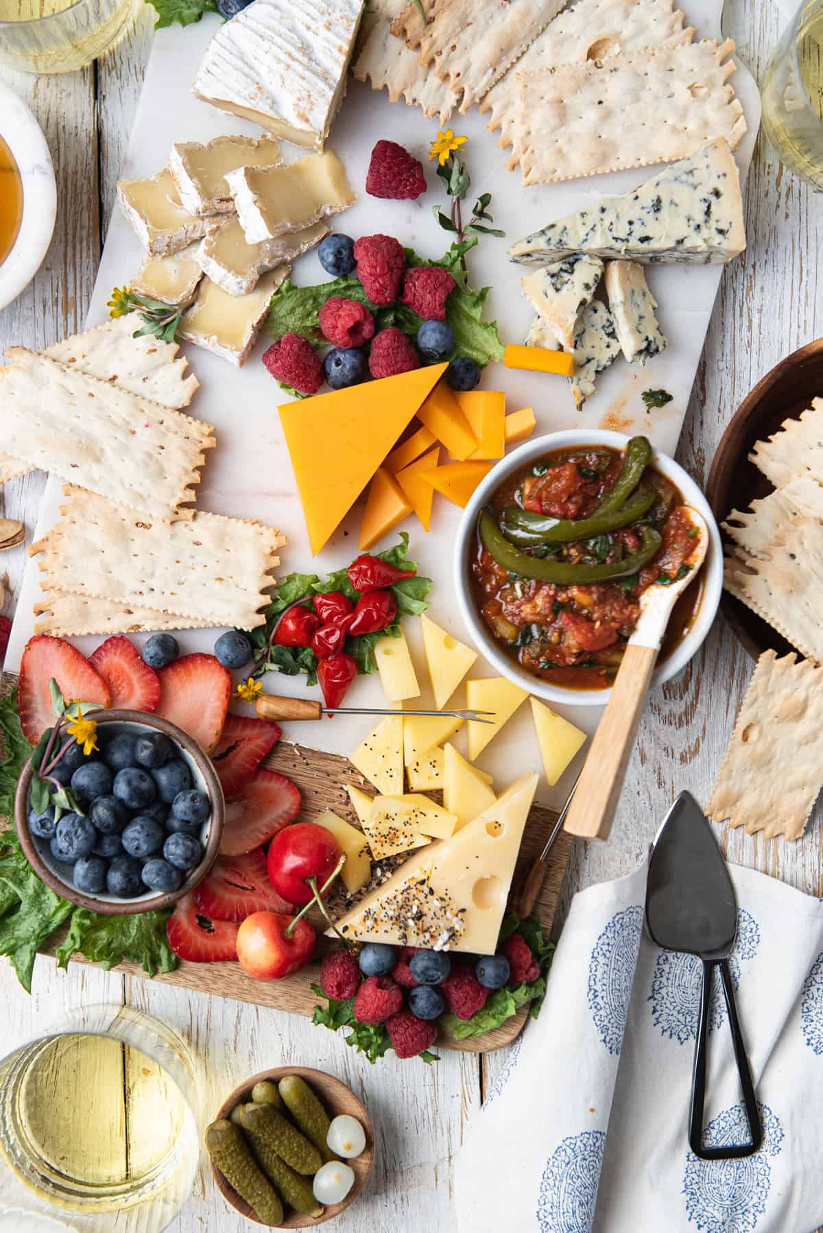 grazing board with cheese, crackers, fruit, and jalapeño jam with spoon