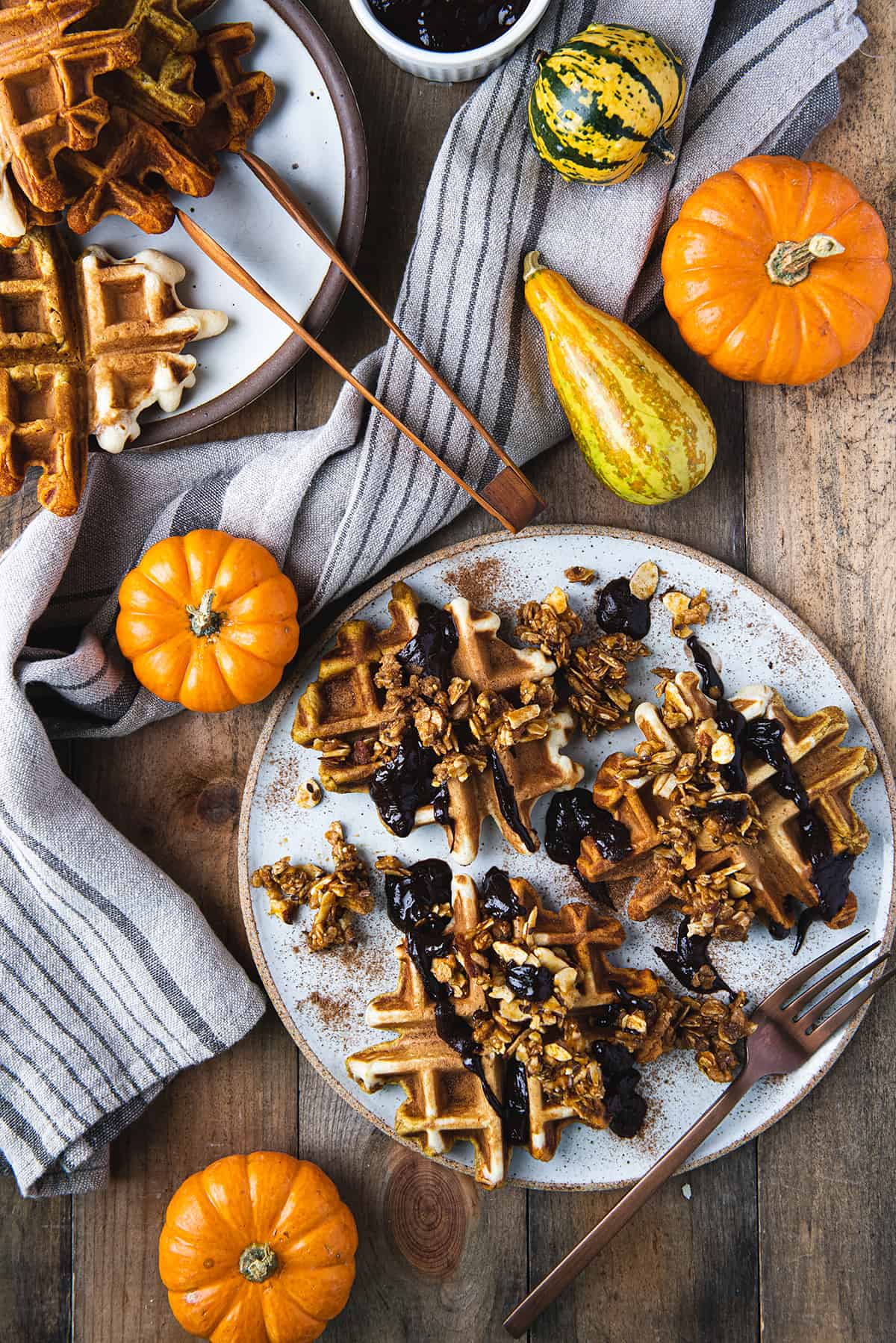 waffles on white plate with fork, linen napkin and orange gourds