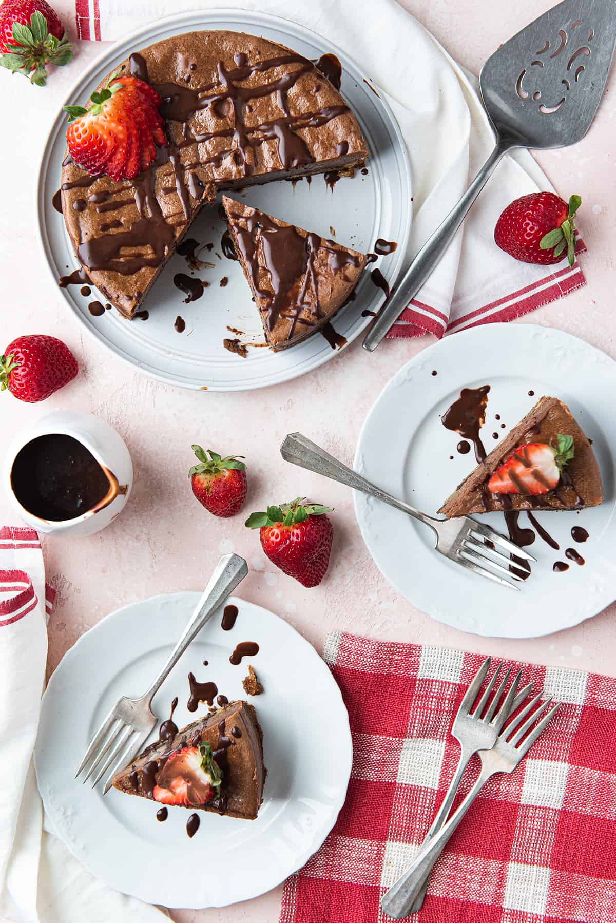 Nutella cheesecake, sliced on pink surface, with slices on white plates + red checked napkin