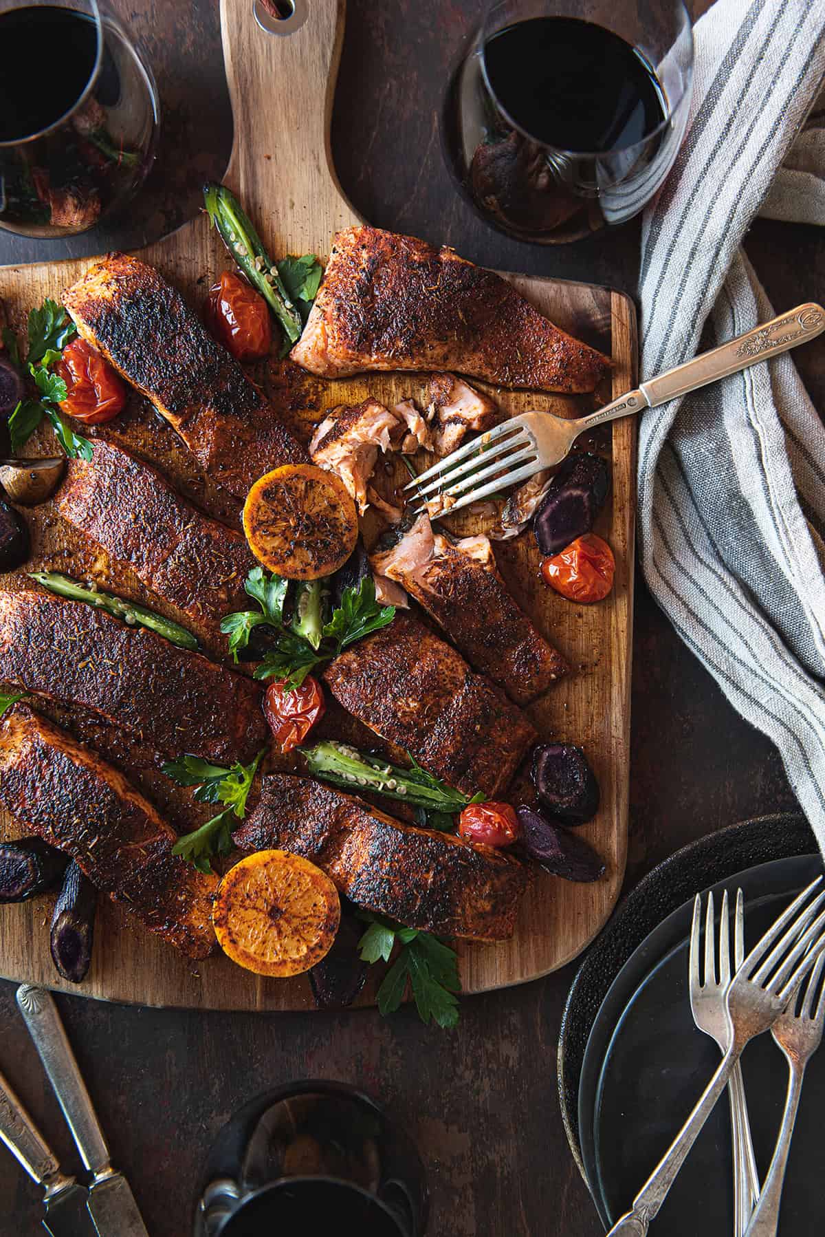 blackened salmon pieces, served on wood board with fork & linen napkin