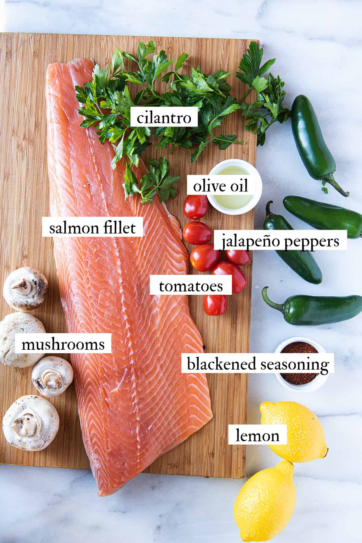 salmon fillet + ingredients for blackened salmon on wooden cutting board & marble surface
