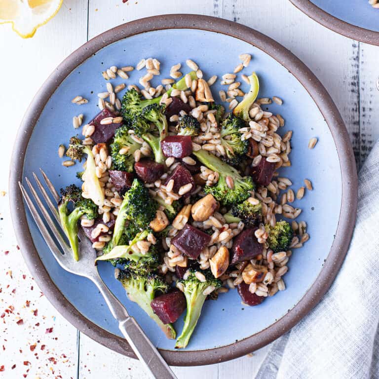 broccoli salad on blue plate with fork + grey napkin