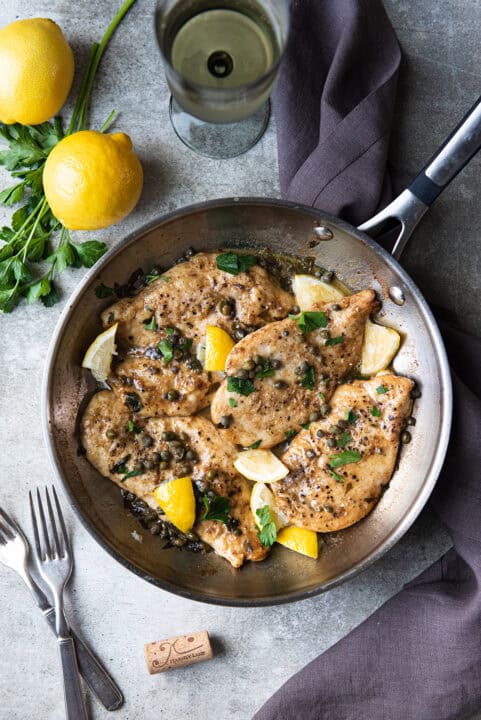 chicken piccata in saut&eacute; pan with lemon wedges + parsley