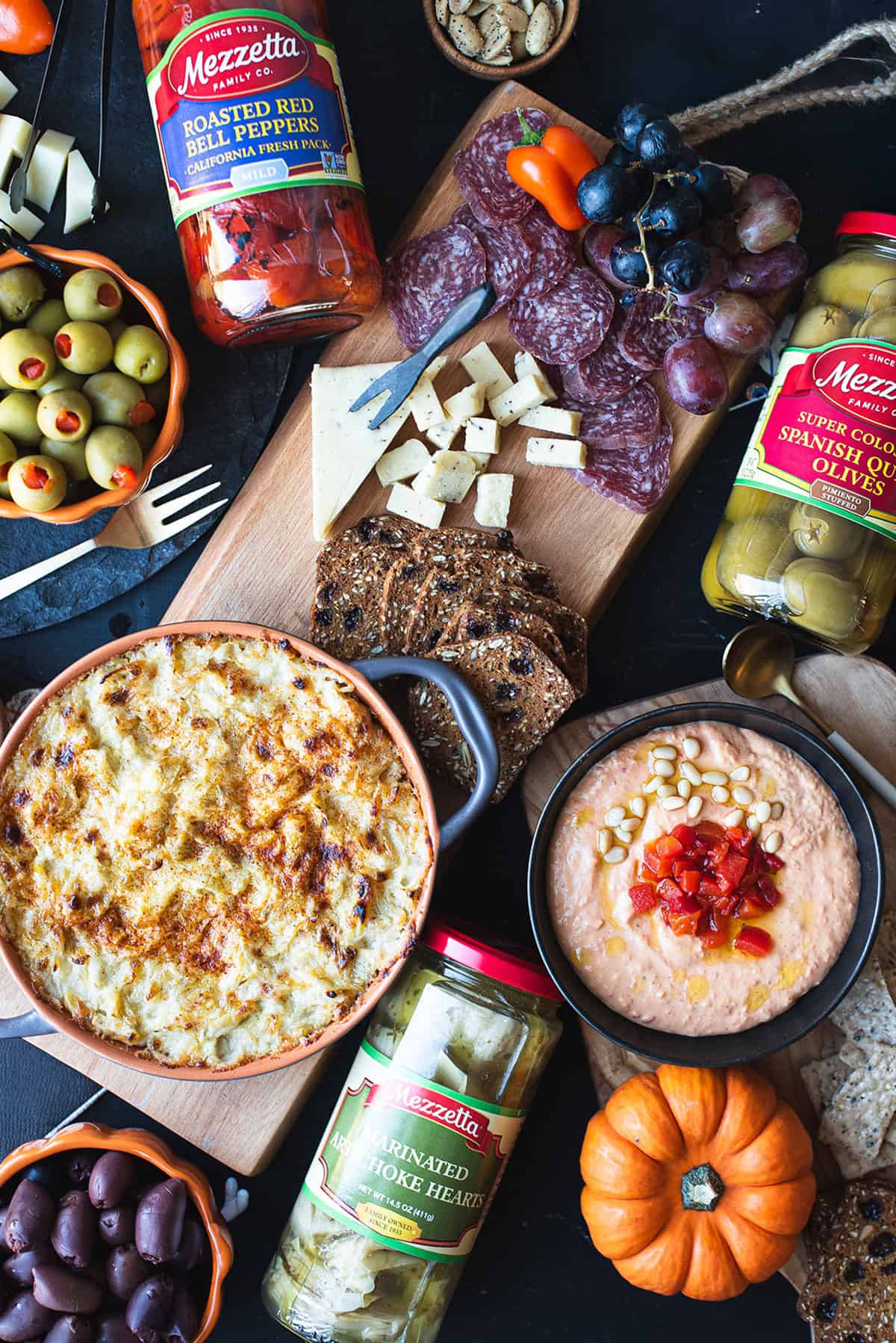 Artichoke dip recipe with Mezzetta marinated artichoke hearts on a party spread with olives, salami, and crusty bread