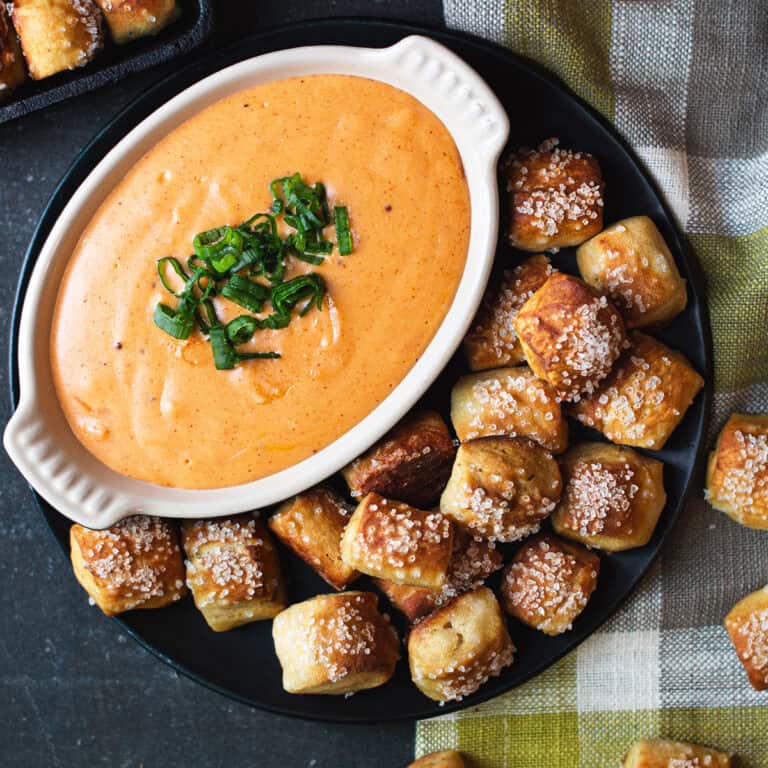 pretzel bites with plate of beer cheese on checked napkin