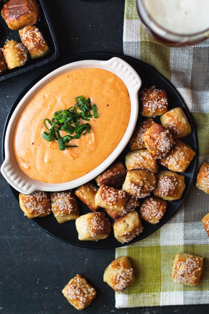 beer cheese dip on platter with pretzel bites & green plaid napkin