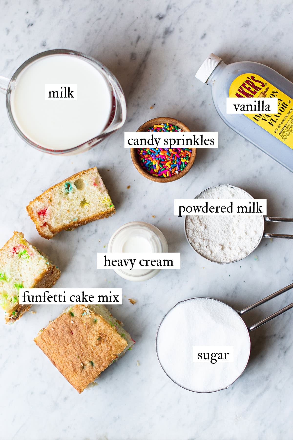ingredients for homemade birthday cake ice cream laid out on a marble counter