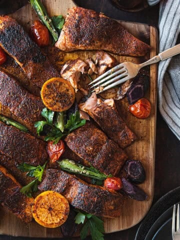 blackened salmon filets, served on wooden board with fork