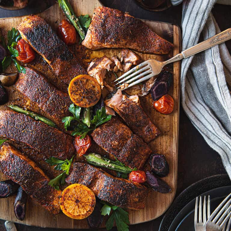 blackened salmon filets, served on wooden board with fork