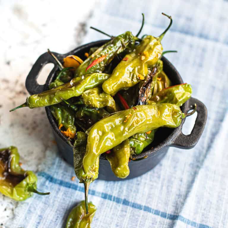 blistered shishito peppers in black serving bowl sprinkled with orange zest