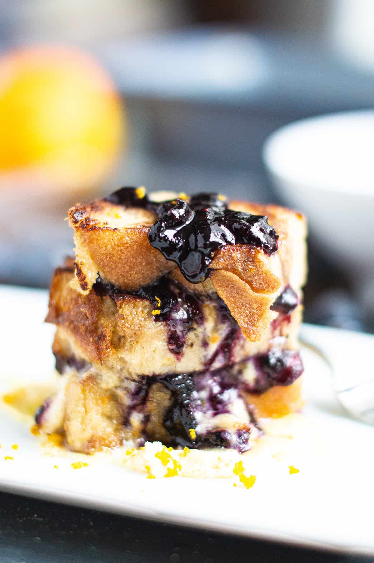 Italian bread pudding topped blueberry compote on white plate
