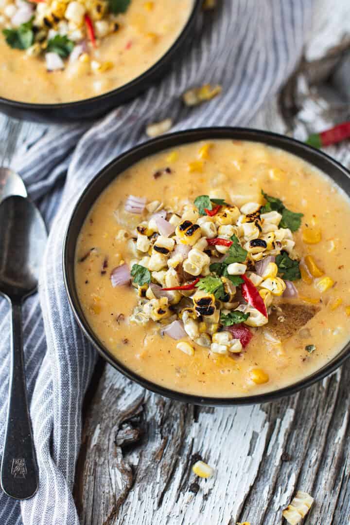 bowl of corn chowder topped with grilled corn and peppers + spoons