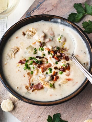 clam chowder in bowl with spoons, linen napkin, and oyster crackers