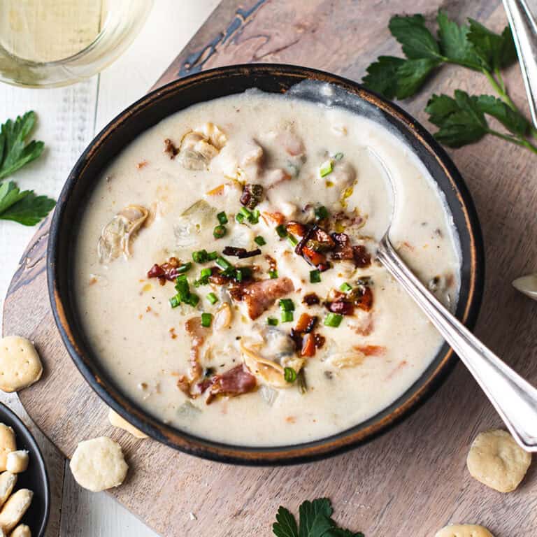 clam chowder in bowl with spoons, linen napkin, and oyster crackers