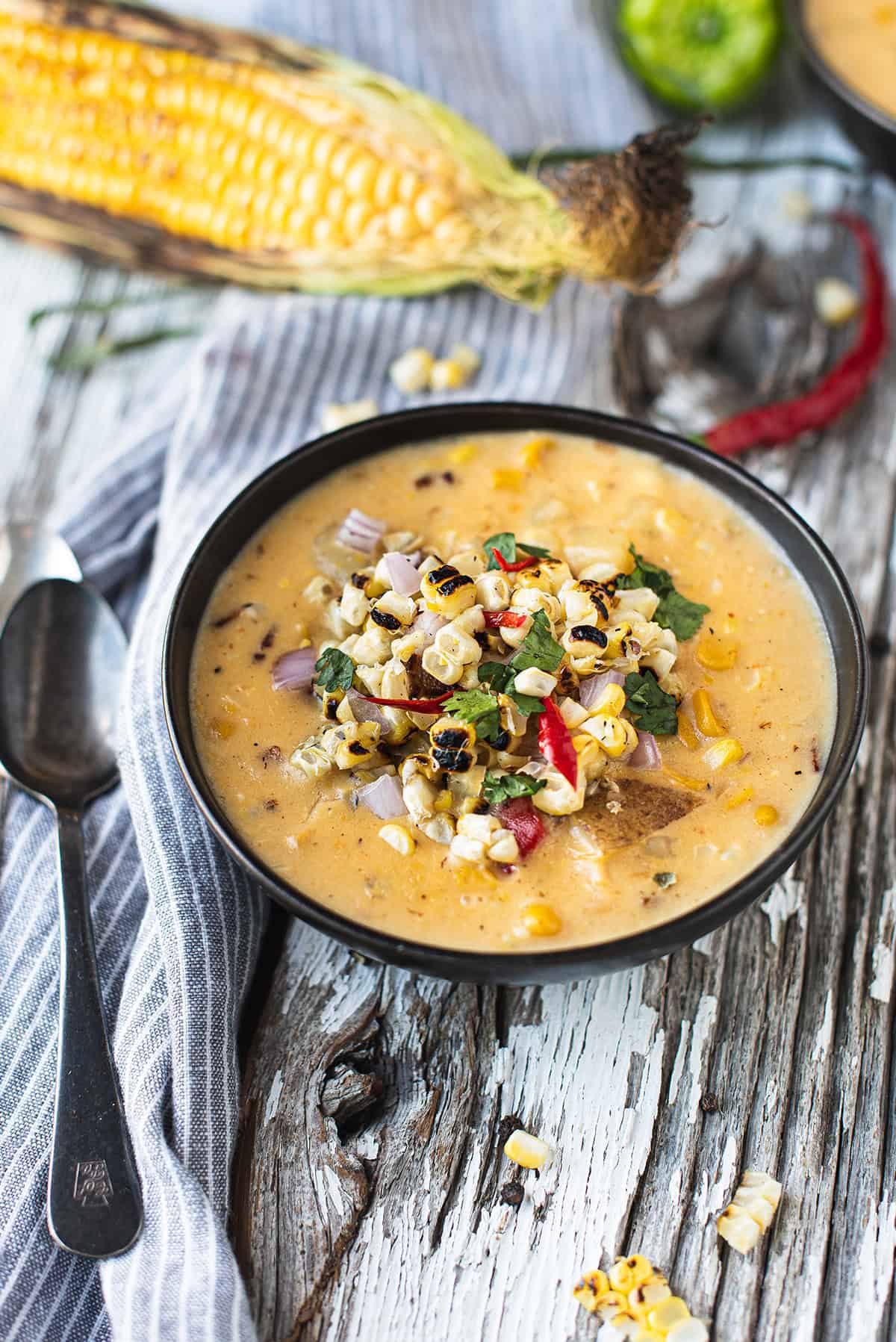 bowl of corn chowder topped with grilled corn and peppers