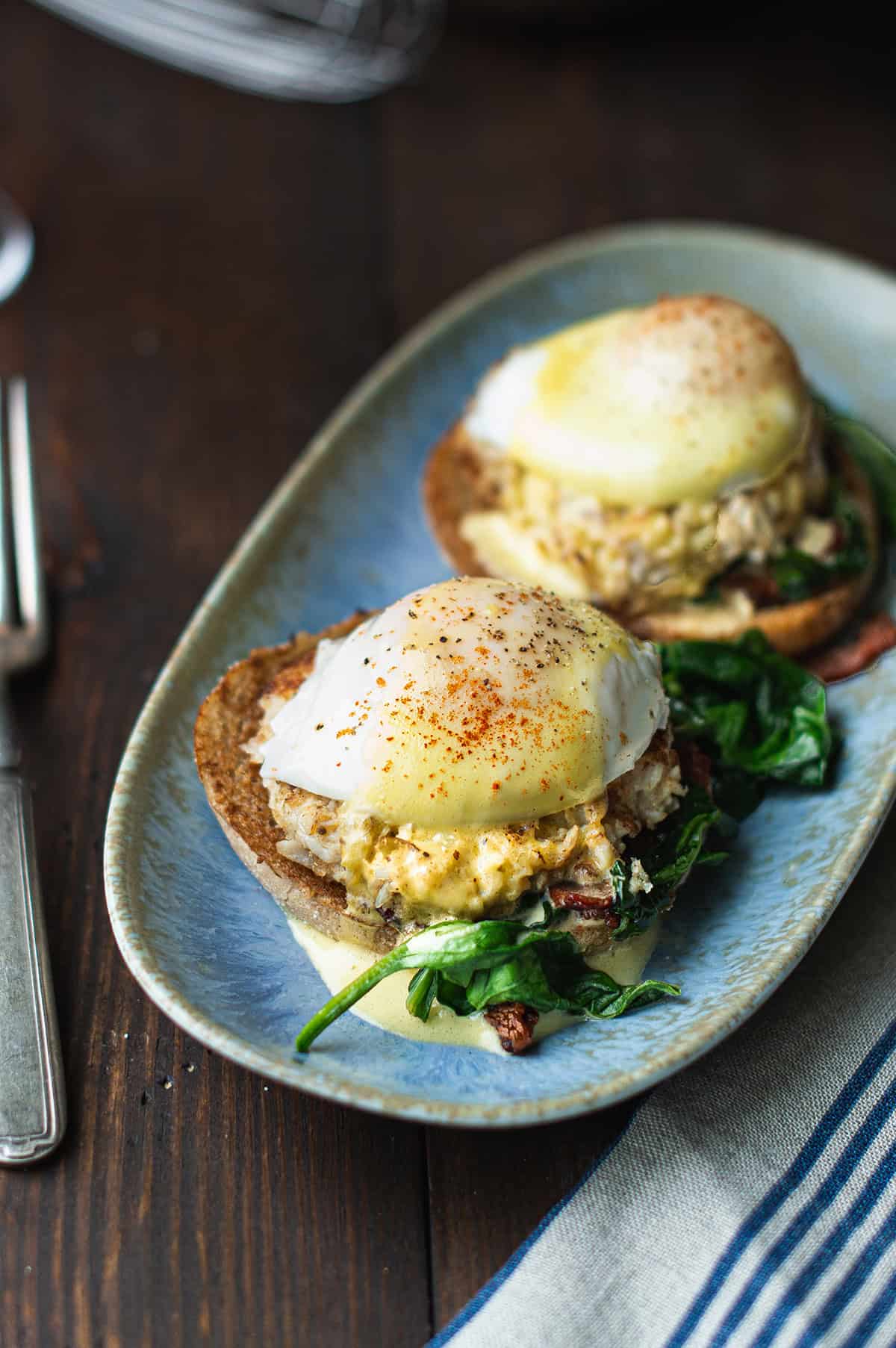 Crab Cake Benedict served on a blue plate with hollandaise sauce