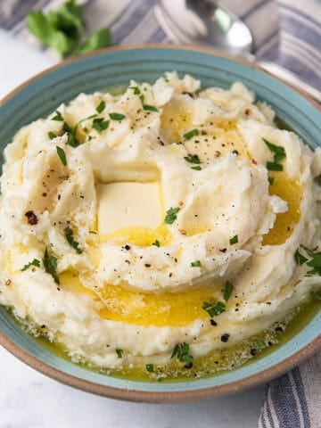 bowl of creamy mashed potatoes with melted pools of butter and blue striped