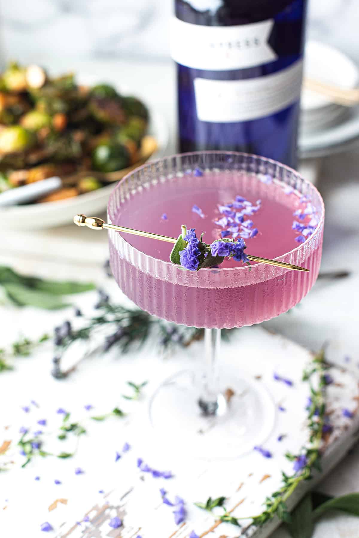purple gin cocktail, garnished and sprinkled with purple flowers