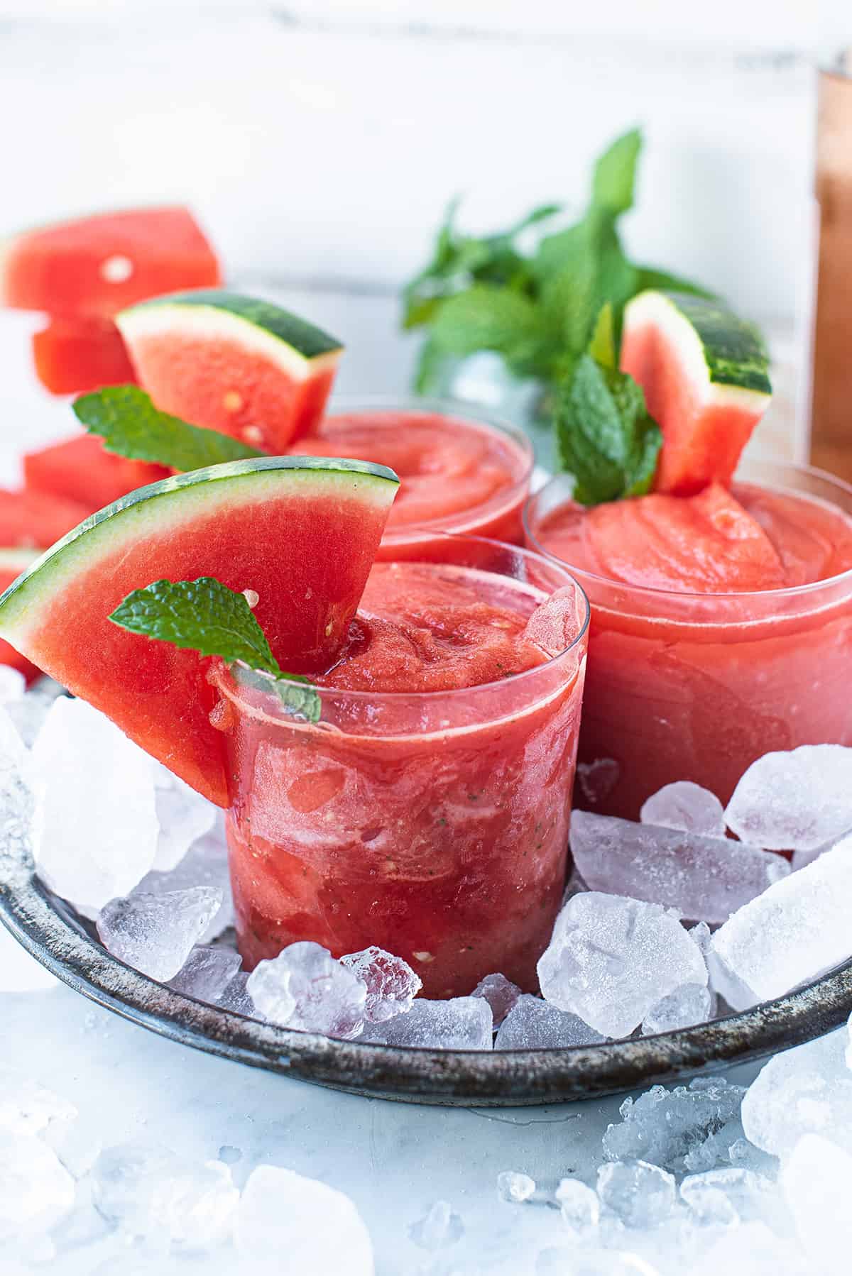 close up of glasses of watermelon frosé in pan of ice