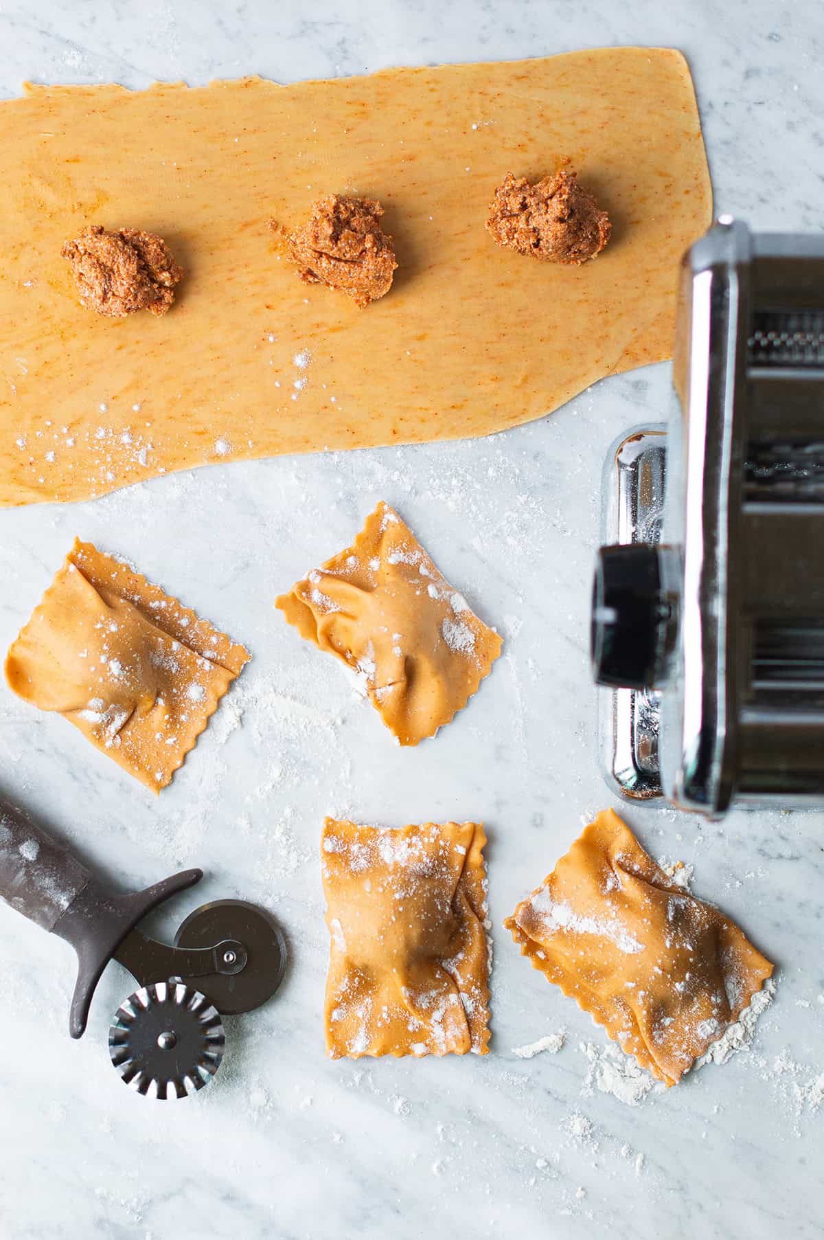 homemade raviolis with cutting tools on marble counter