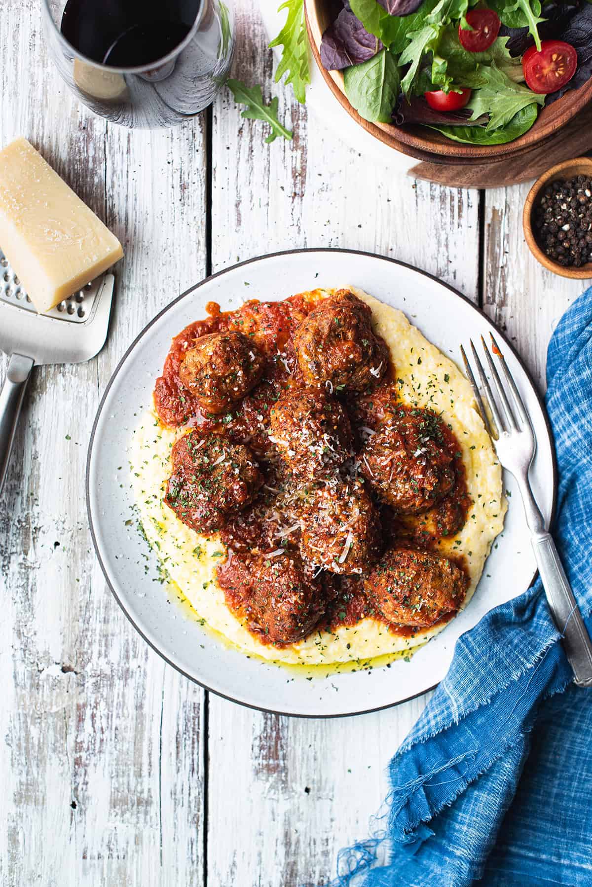 meatballs served over polenta on white ceramic plate + red sauce on top