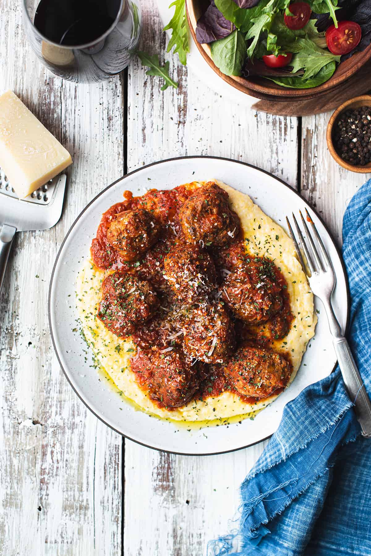 meatballs served over polenta on white ceramic plate + red sauce on top