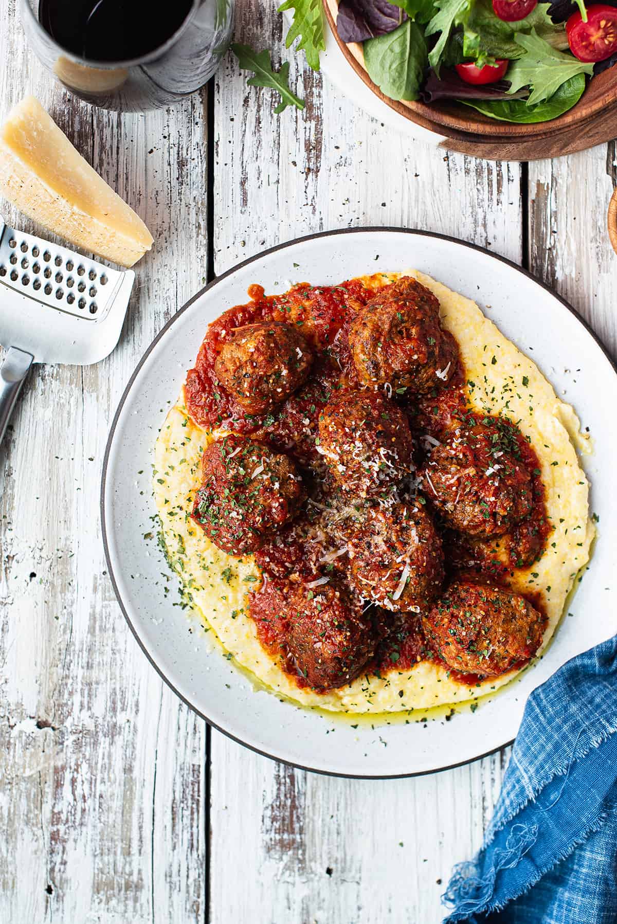 meatballs served over polenta on white plate, topped with tomato sauce