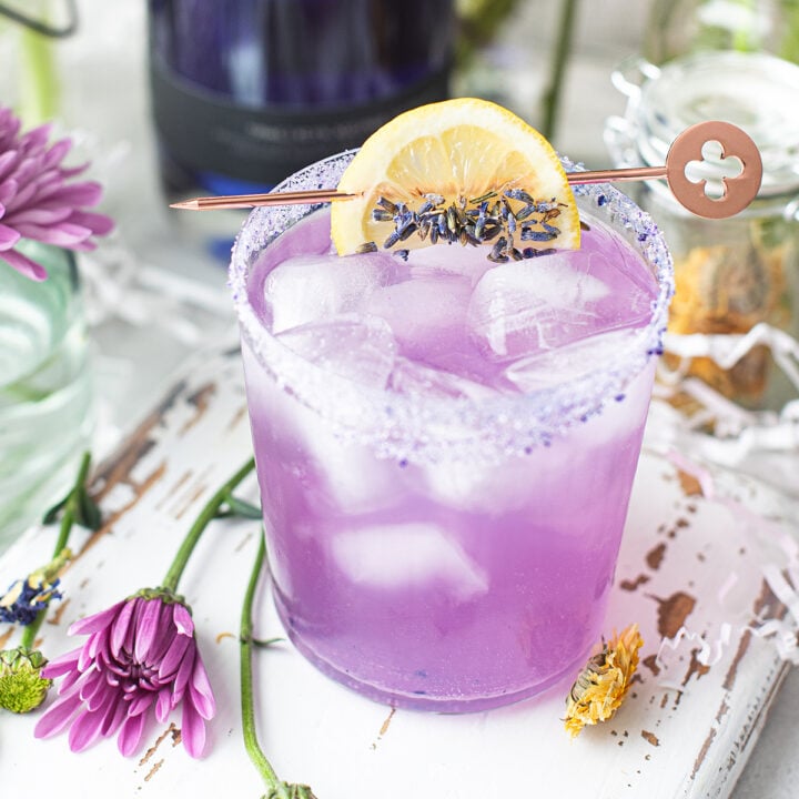 lavender lemonade cocktail, garnished with lemon wedge and flowers