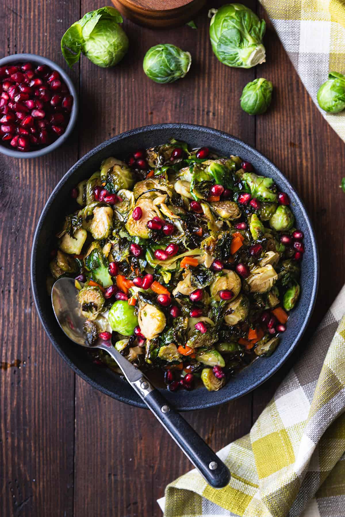 bowl of maple roasted Brussels sprouts on wooden table with serving spoon