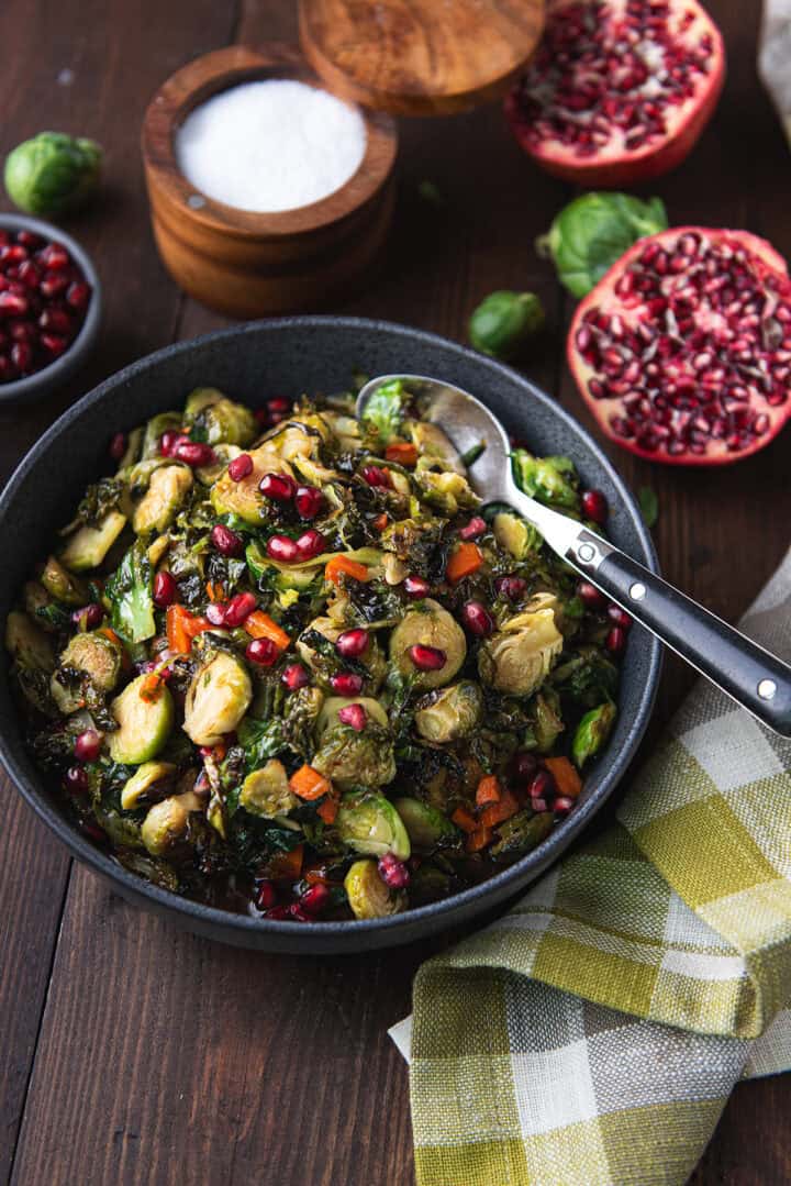 bowl of maple roasted Brussels sprouts on wooden table with serving spoon