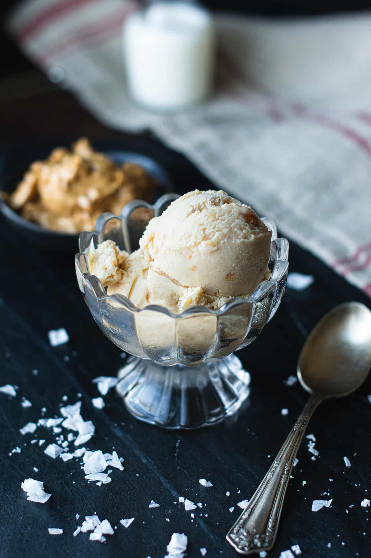 peanut butter ice cream served in glass dish with spoon, red striped napkin, and bowl of peanut butter