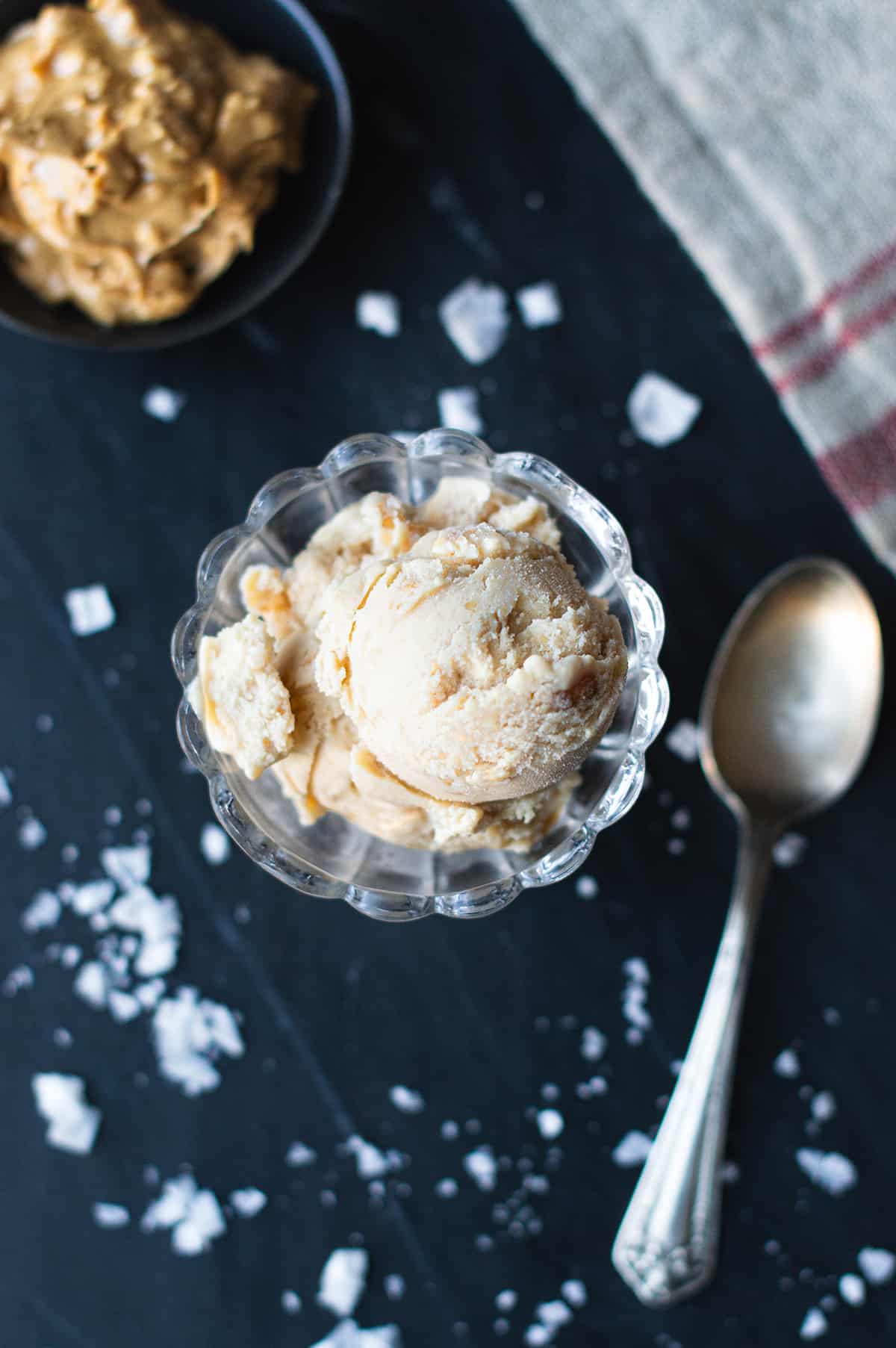 peanut butter ice cream served in glass dish with spoon, red striped napkin, and bowl of peanut butter