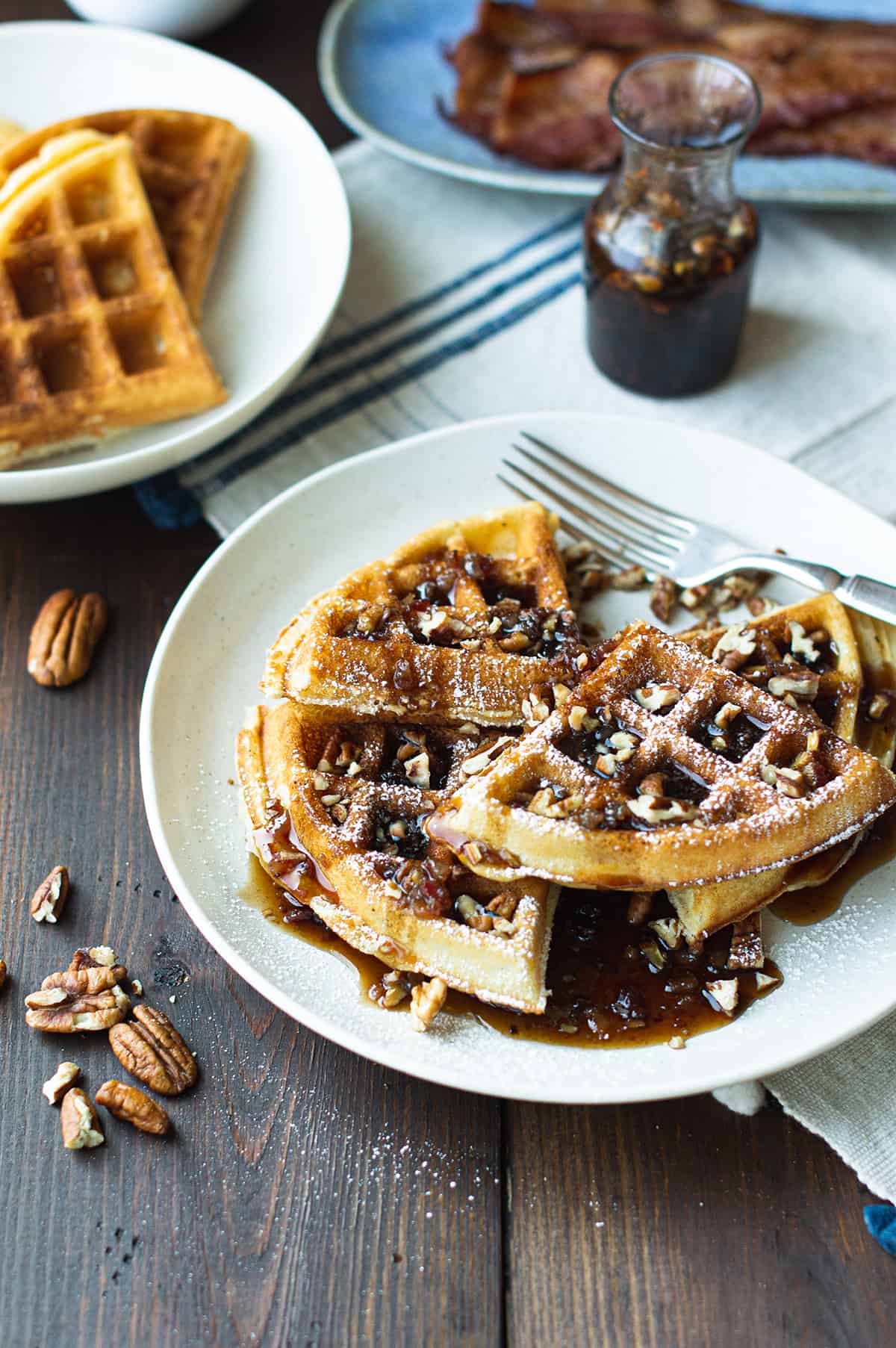 pecan waffles on white plate with fork, maple syrup 