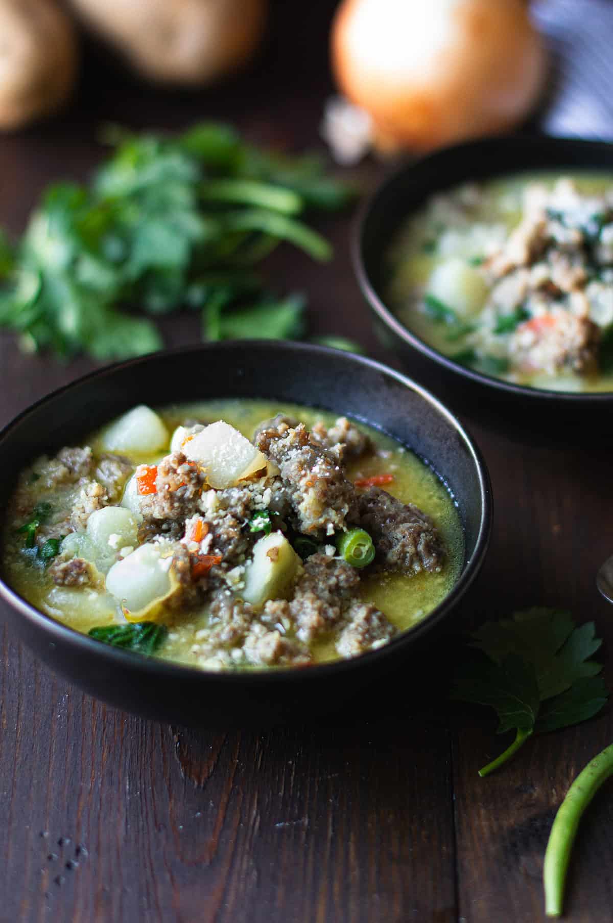 Italian sausage soup served in a bowl with potatoes and vegetables