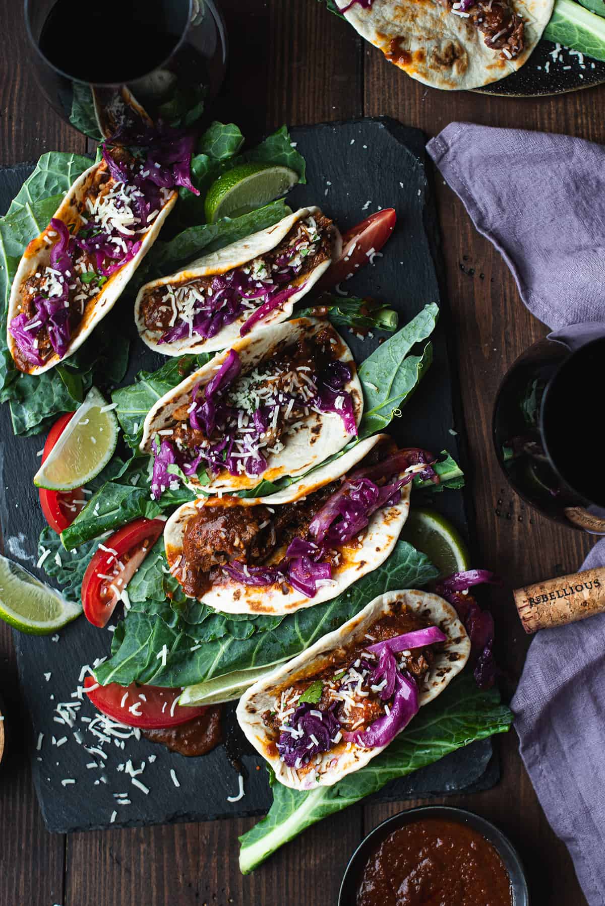5 short rib tacos on black platter with red cabbage & cheese