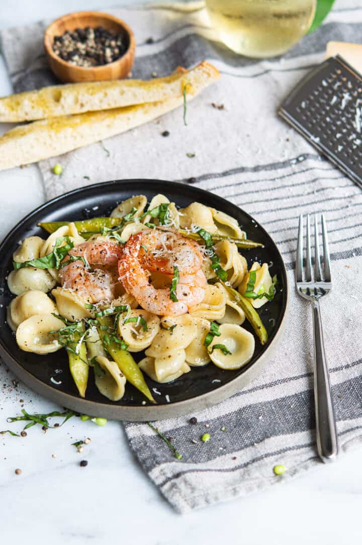 Shrimp Orecchiette on black plate with linen napkin, bread sticks, and fork