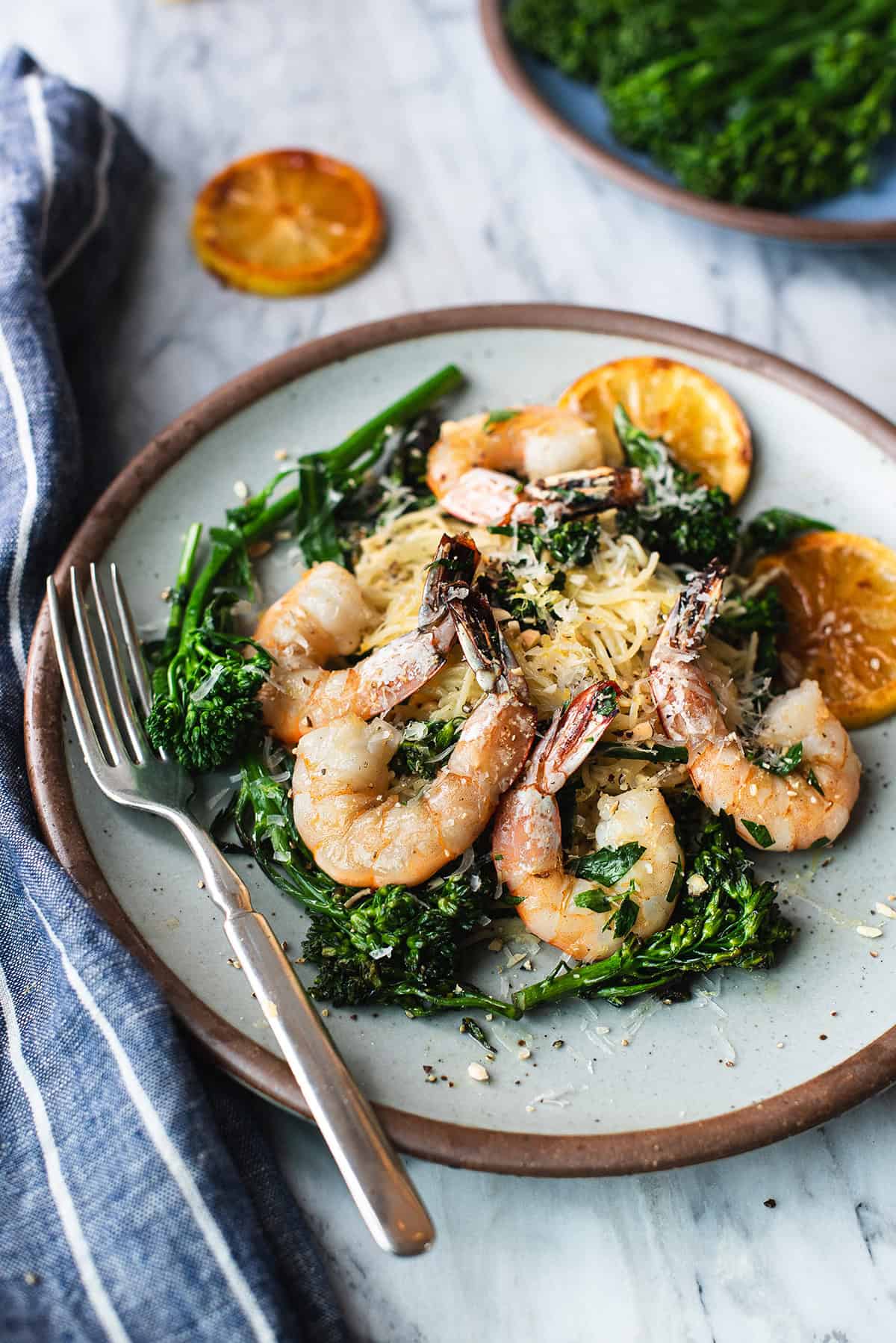close up of lemony shrimp pasta on white plate with fork