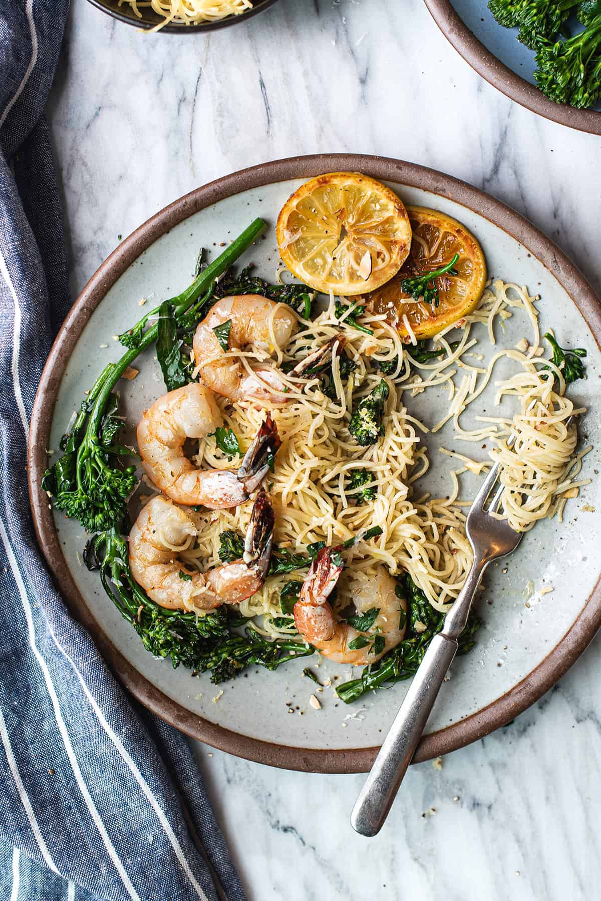 lemony shrimp pasta on white plate, twirled on fork + blue napkin