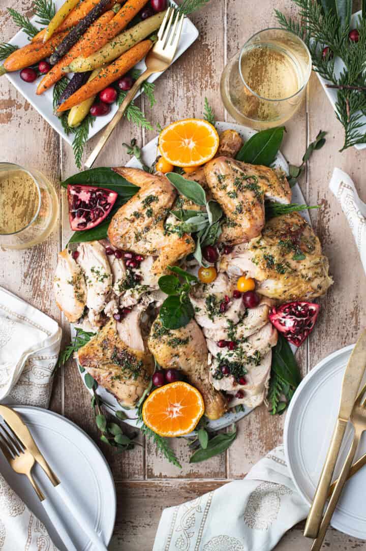 roasted chicken sliced on holiday table with oranges, pomegranate, herbs