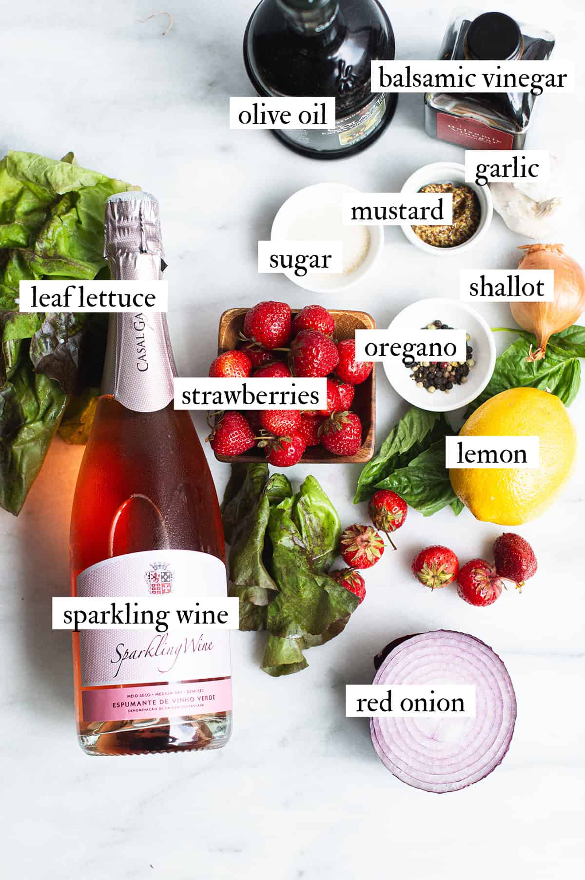 ingredients for strawberry salad with champagne vinaigrette spread out on white countertop
