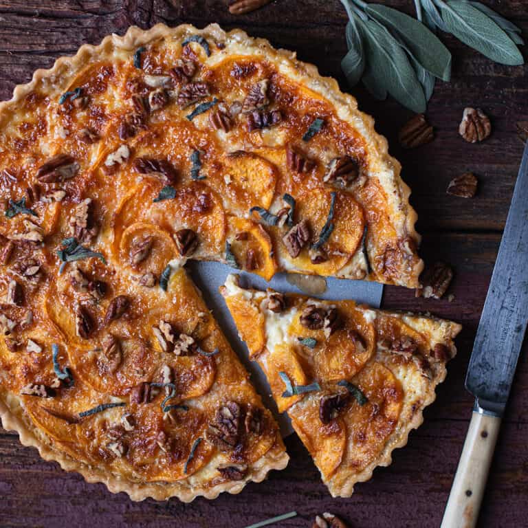 sweet potato tart on wooden table with one slice cut out + knife