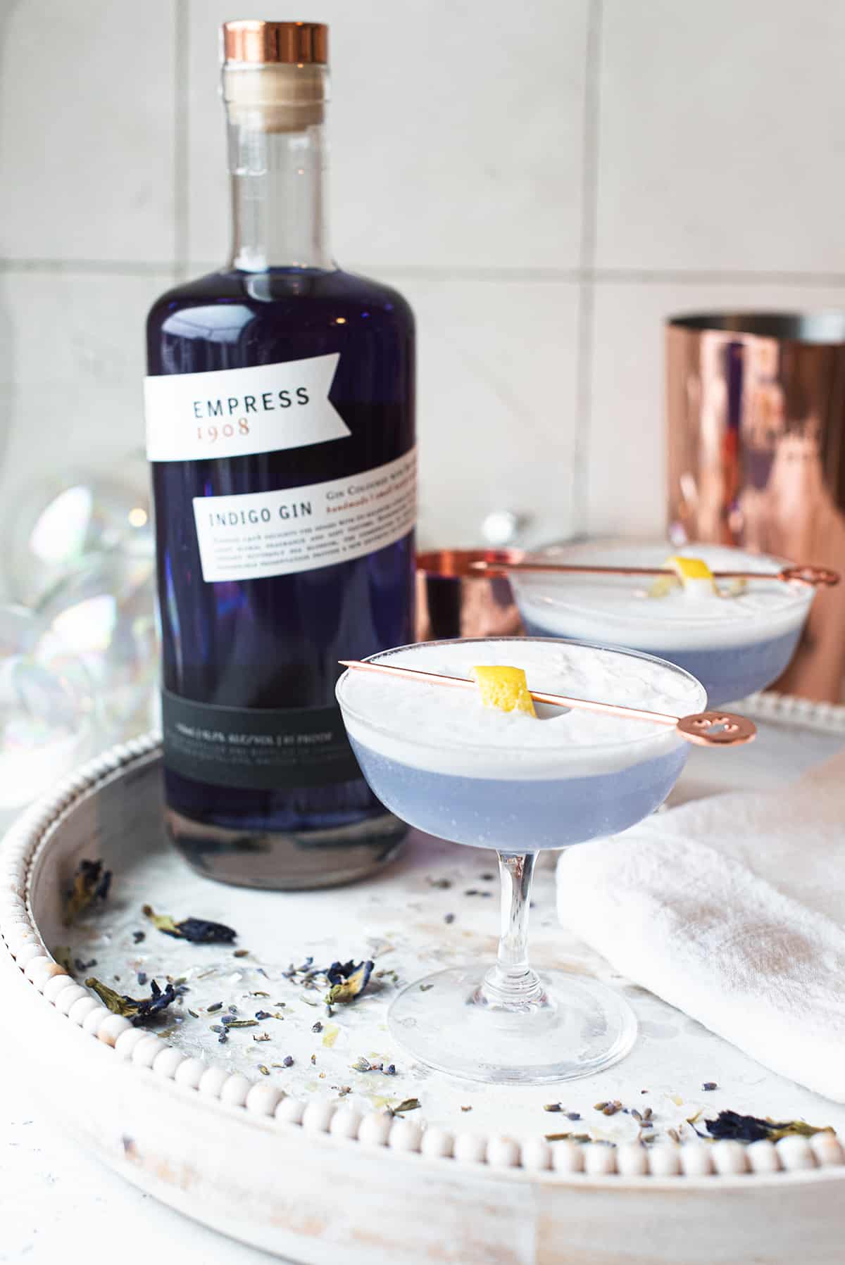 blue frost fizz gin cocktails on white serving tray + bottle of Empress Gin
