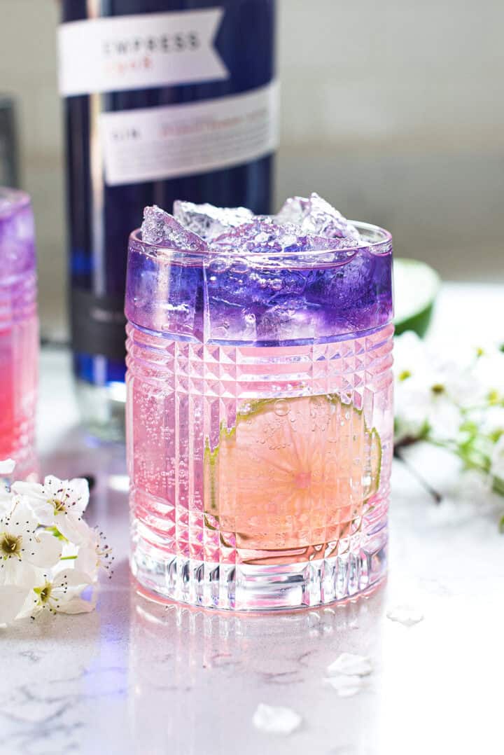 empress gin cocktail in rocks glass on white countertop with lime slice
