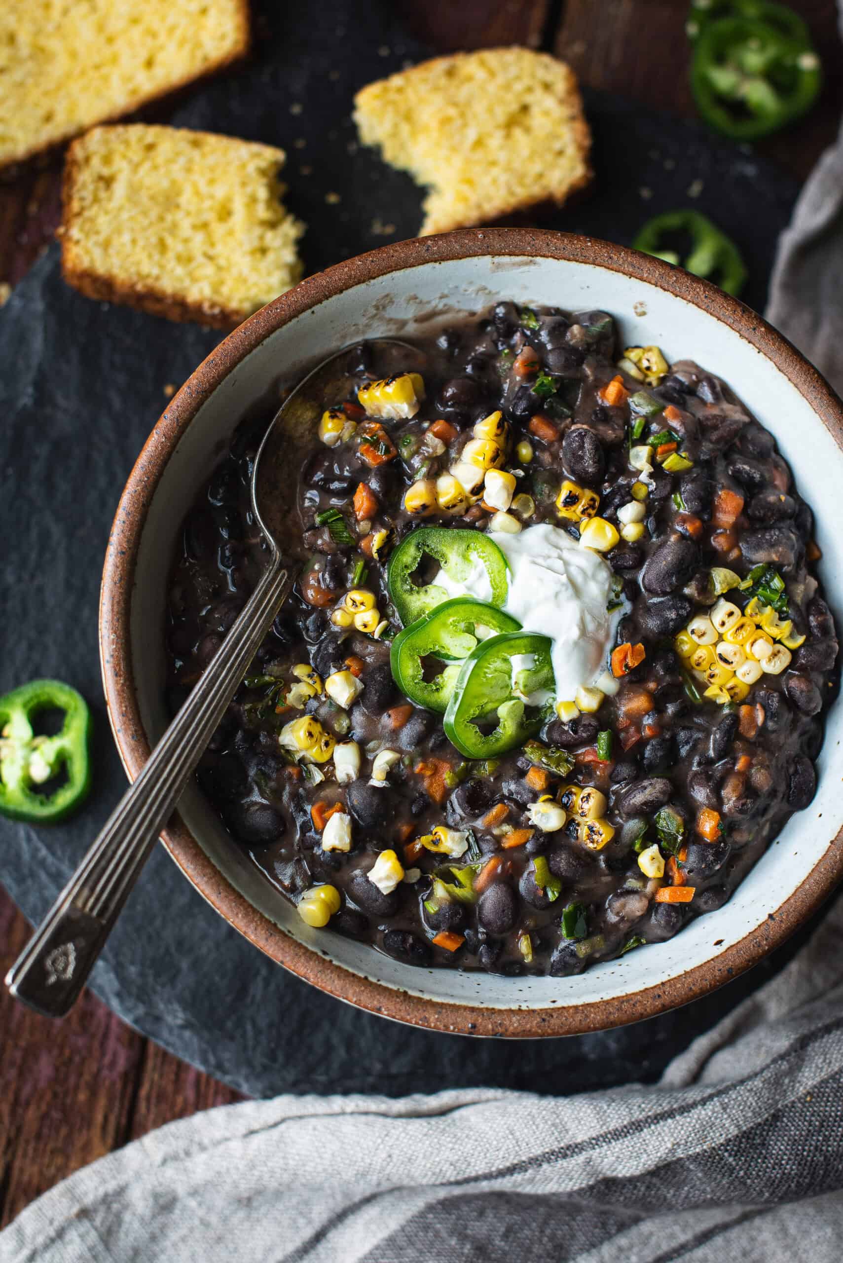 bowl of black bean soup with spoon, topped with pepper slices and sour cream